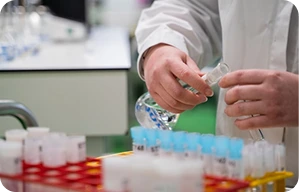 A lab technician pouring liquid from viles